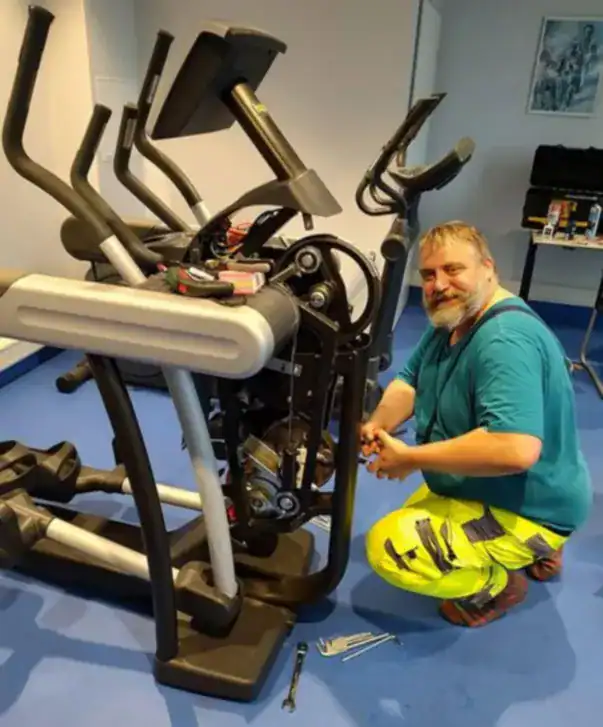 Technician performing professional repairs on gym fitness equipment